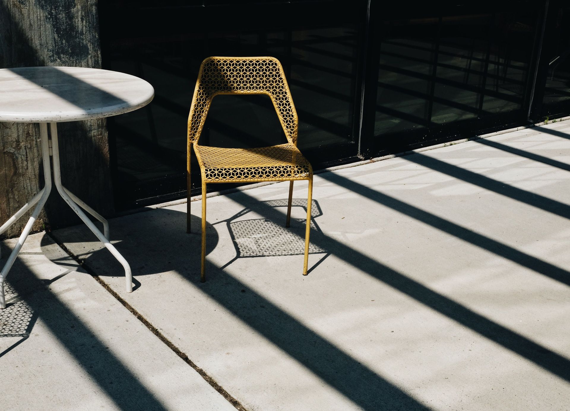 Stylish outdoor patio featuring a modern chair and table set in bright sunlight.