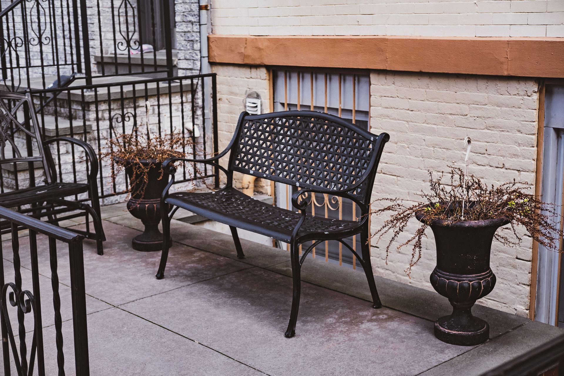 A stylish outdoor terrace featuring a decorative metal bench and potted plants, perfect for urban relaxation.
