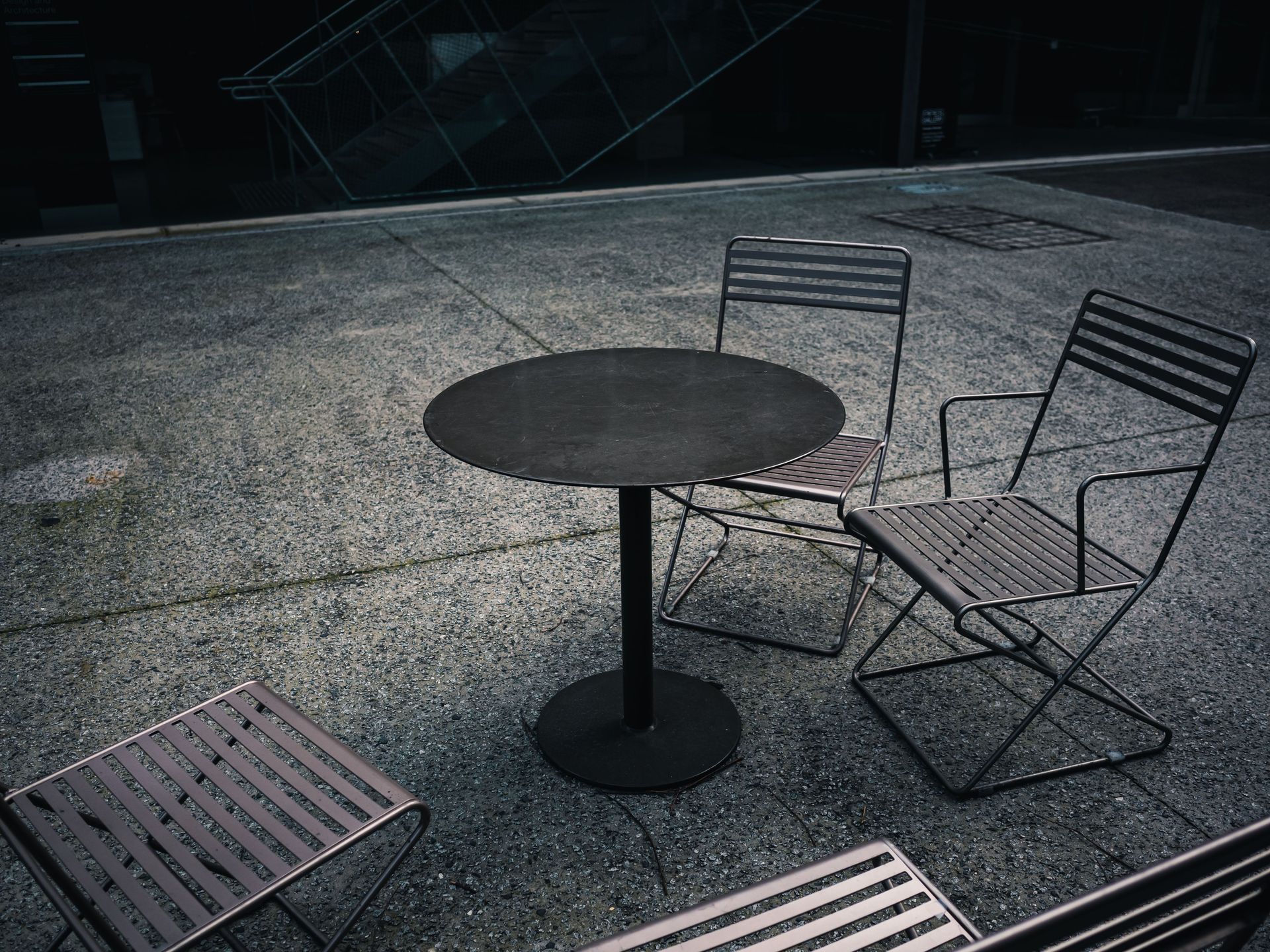 Empty metal chairs and table in a modern outdoor setting, perfect for urban themes.